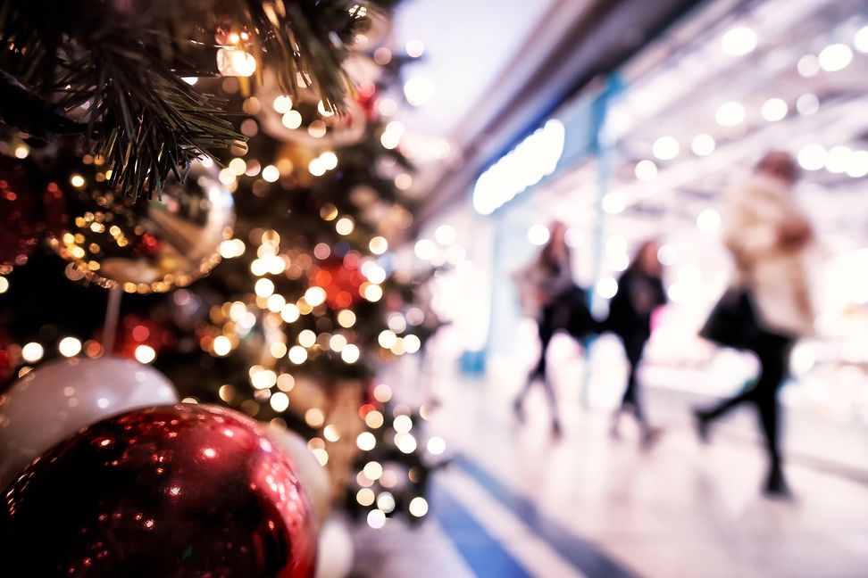 Menschen in einem Einkaufszentrum gehen an einem geschmückten Weihnachtsbaum vorbei