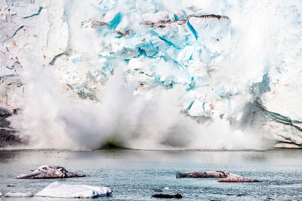 Teile eines Eisbergs oder Gletschers stürzen ins Wasser