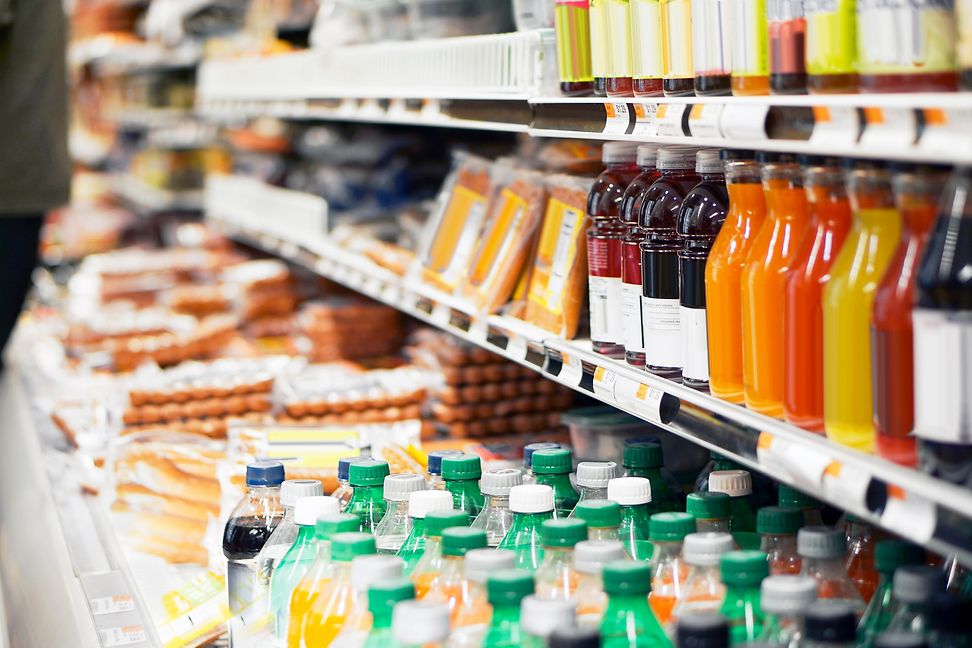 Ein Supermarktregal mit Getränkeflaschen und verpackten Konsumgütern.