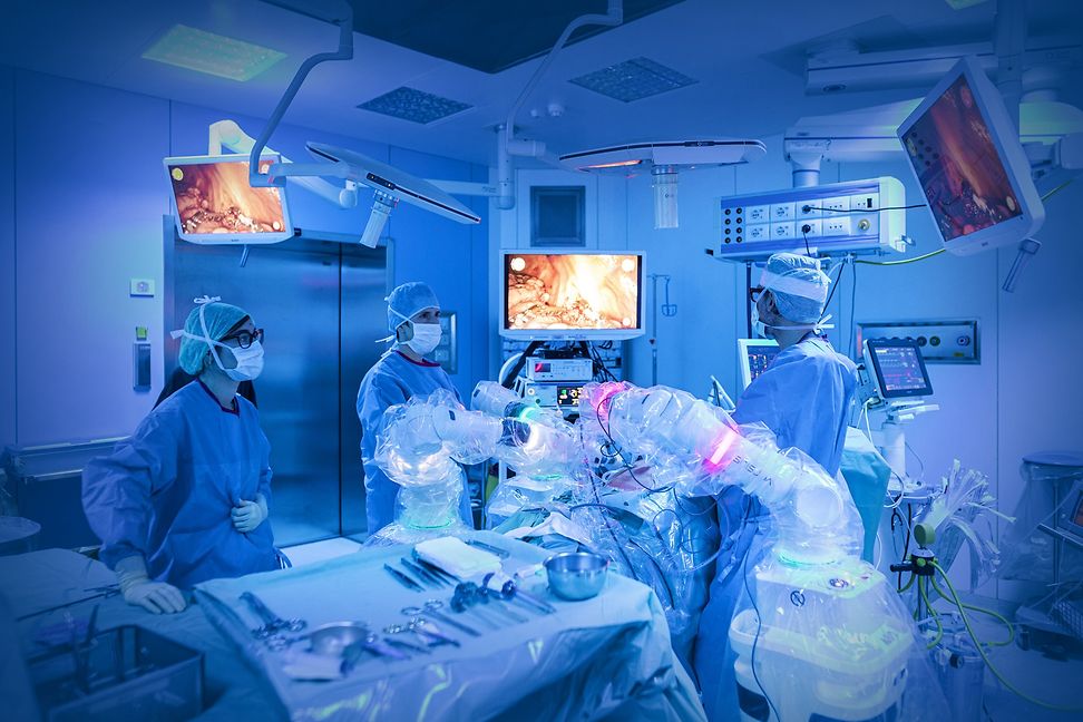Robots working alongside surgical staff on a patient in an operating theatre.