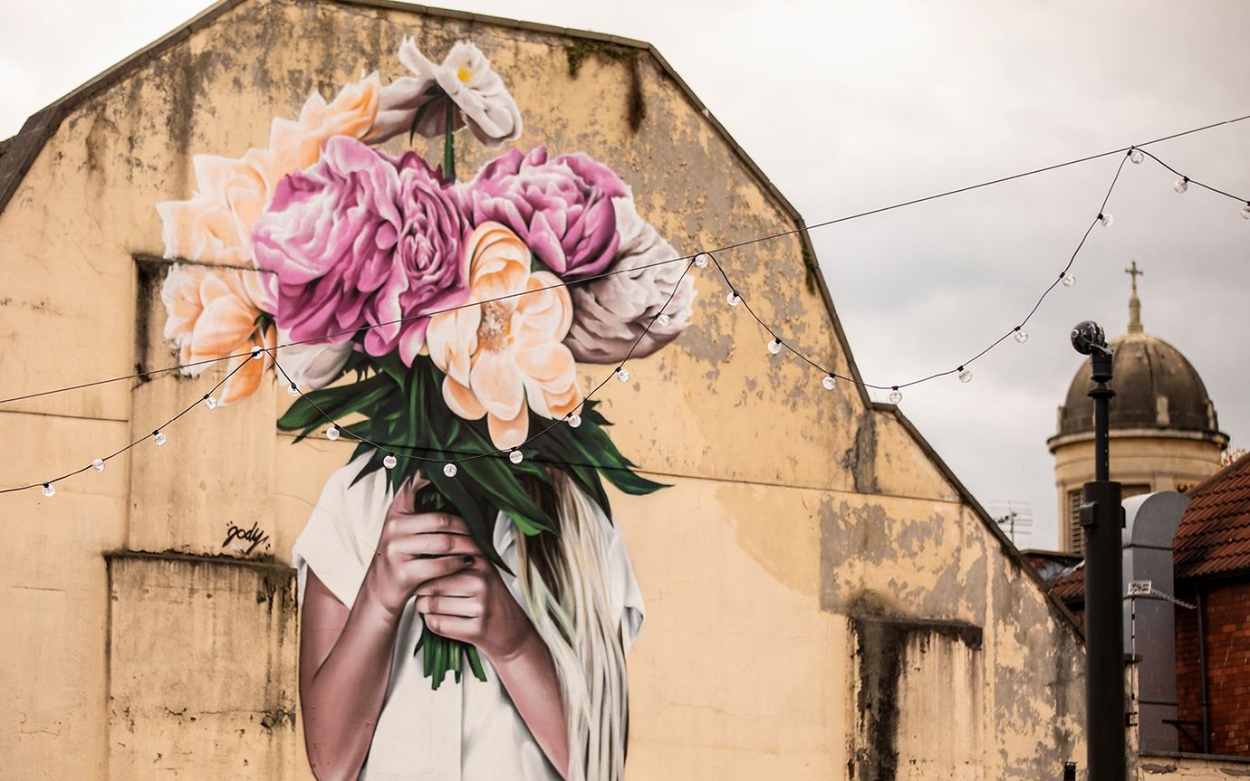 Street art; a woman holds a bouquet of flowers in front of her face