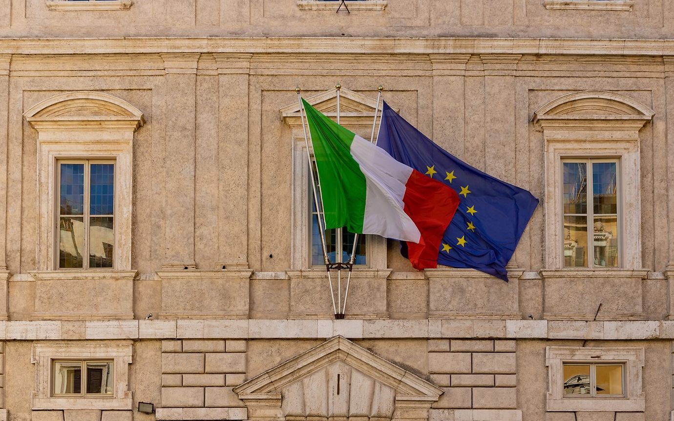 Ein altes Gebäude in Nahaufnahme mit der italienischen und der EU-Flagge.