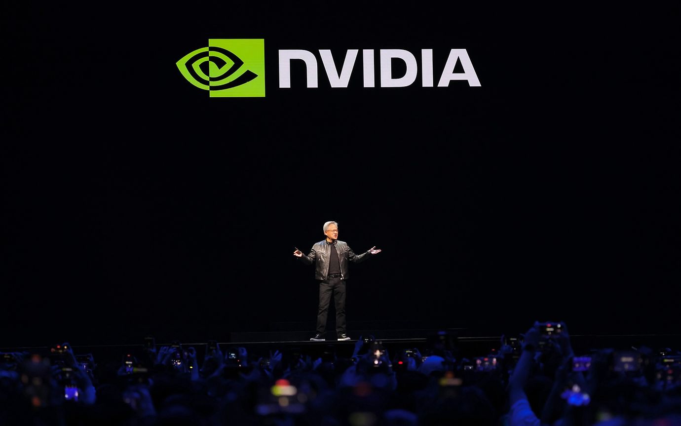 Ein Mann spricht auf einer dunklen Bühne vor dem Schriftzug "Nvidia".