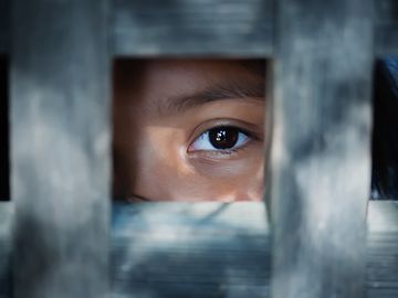 Das Auge eines Kindes blickt aus einem hölzernen Rahmen.