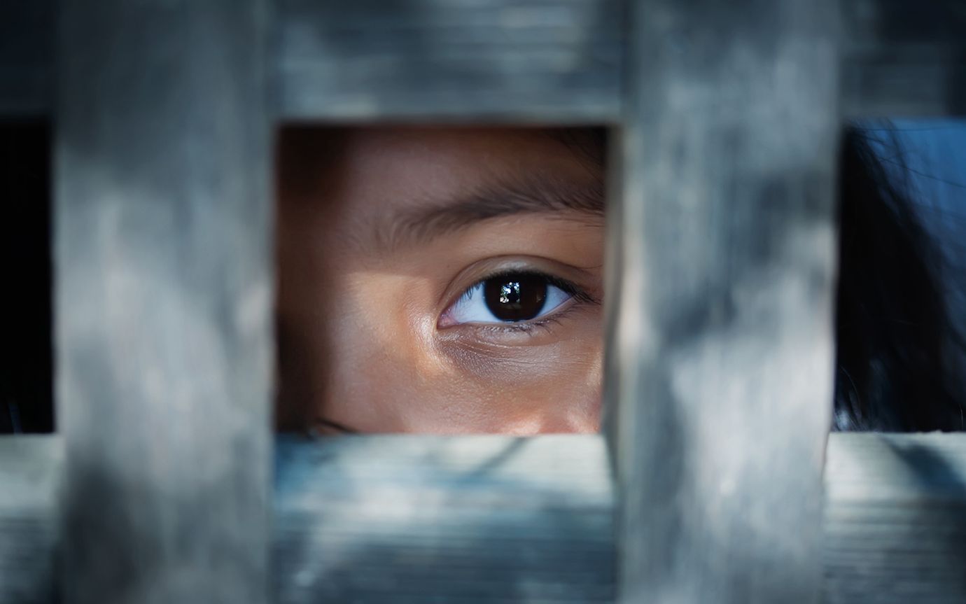 Das Auge eines Kindes blickt aus einem hölzernen Rahmen.