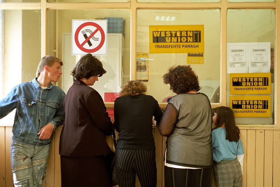 Eine Familie steht an einem Schalter mit der Aufschrift "Western Union".