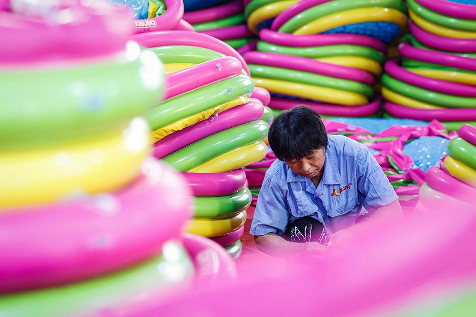 A man surrounded by piles of large, brightly coloured plastic rings.