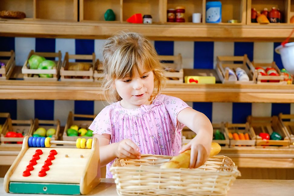 A child plays with a wooden pretend play grocery store