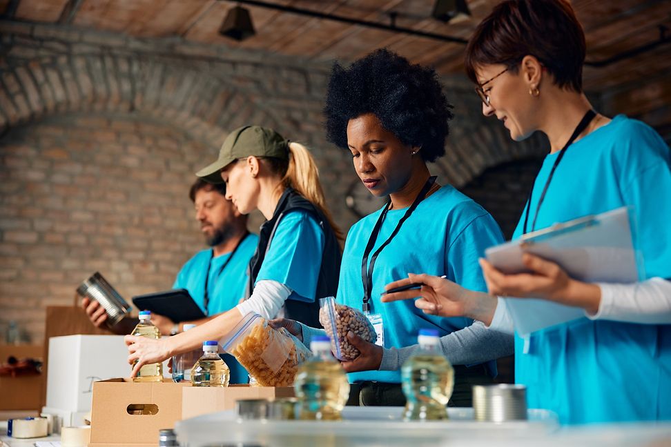 Four people in turquoise T-shirts are packing goods into crates.