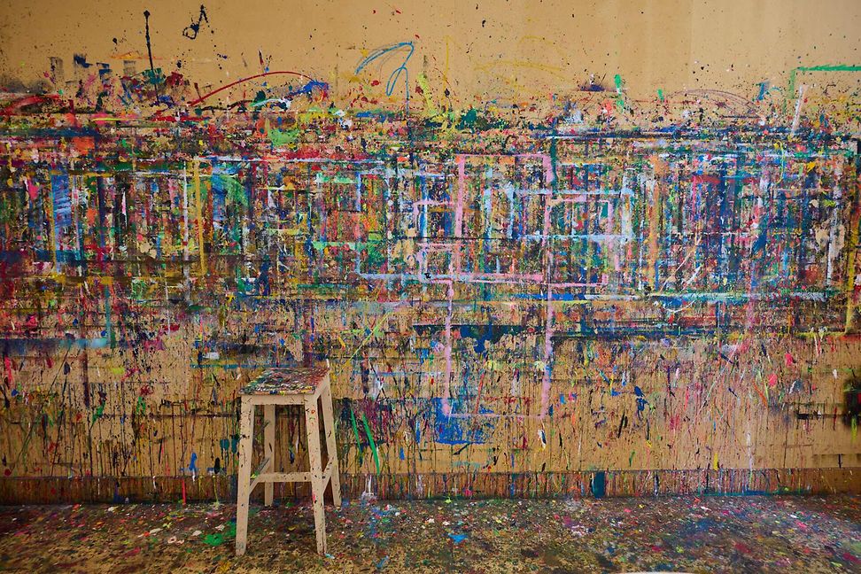 A large wall is covered with colourful, chaotic splashes of paint. The colours and shapes seem unstructured and random.