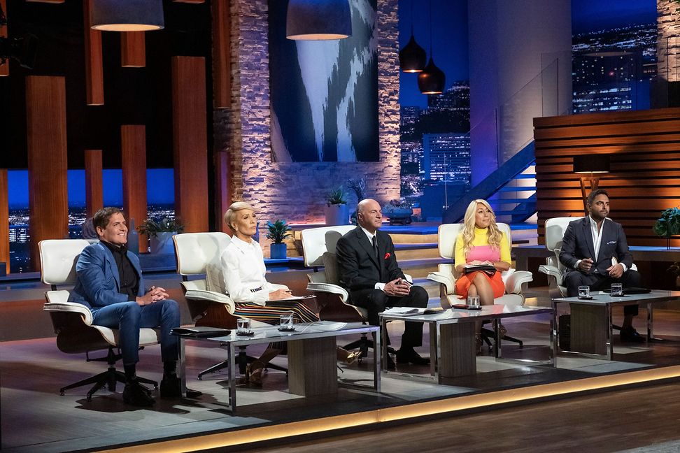 A group of five divers individuals are setting in a TV studio setting in comfy chairs listening to a presentation.