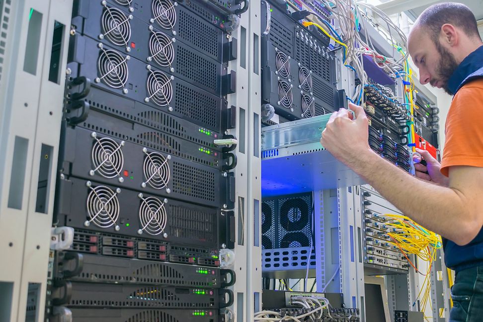 A man examines a large electronic system by pulling out a component.