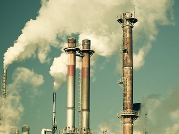 Factory smokestack with cloud of smoke against the sky