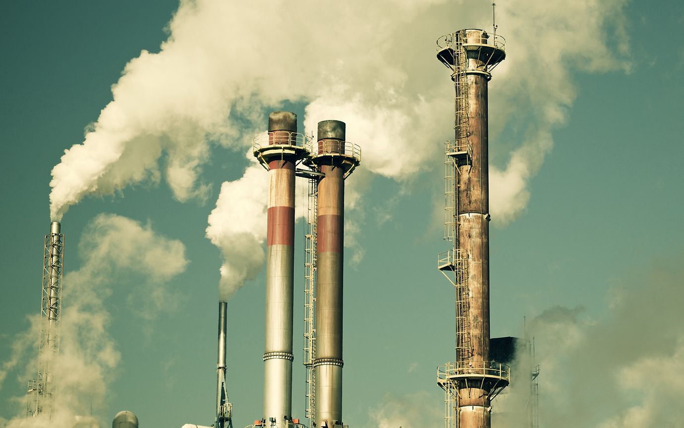 Factory smokestack with cloud of smoke against the sky