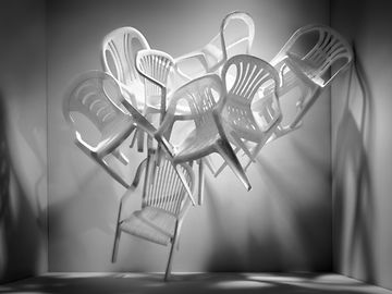 White plastic chairs form a pile in an empty room.