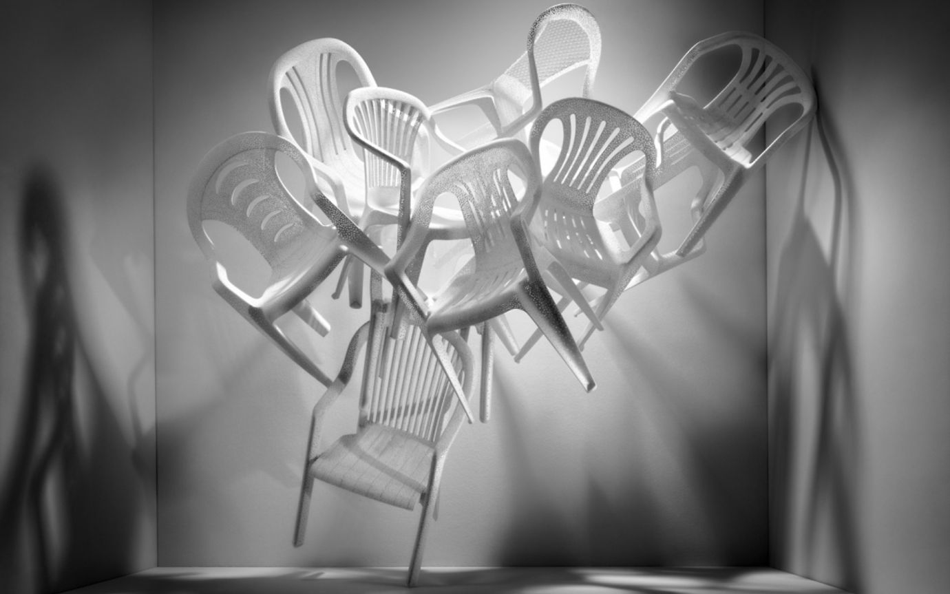 White plastic chairs form a pile in an empty room.