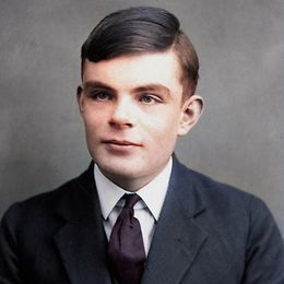 A young man in a 1930s suit with side-parted hair stands against a gray background and looks to the right.